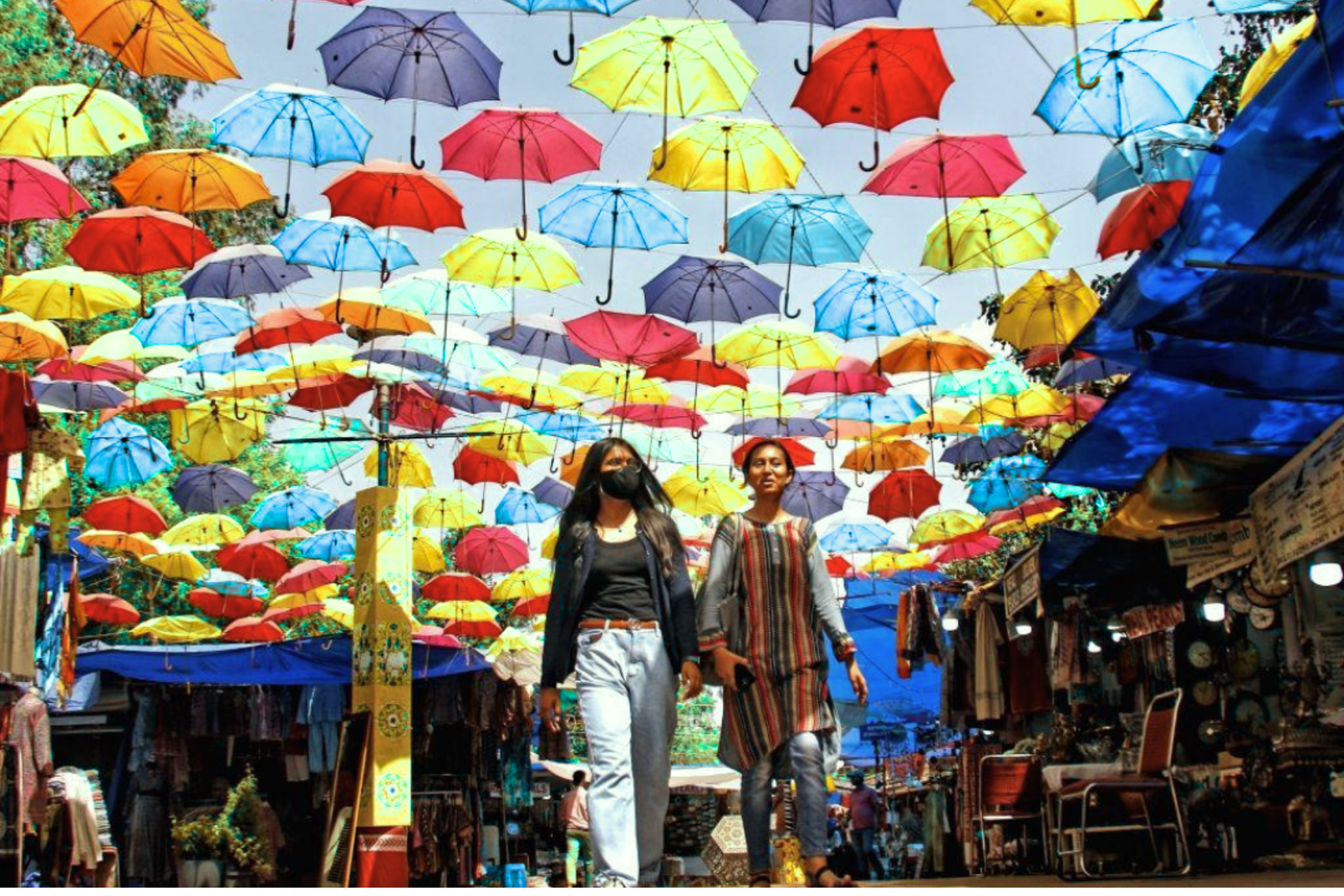 Visitors and local shoppers walking through an outdoor market in Delhi.