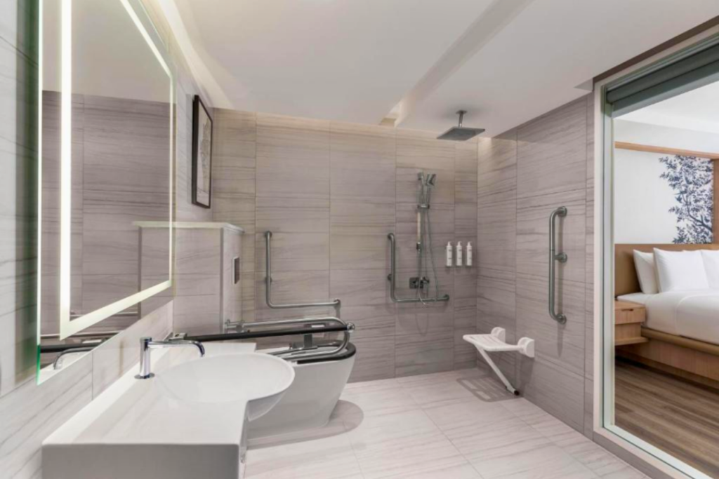 An accessible hotel bathroom with a step-free shower and grab rails.